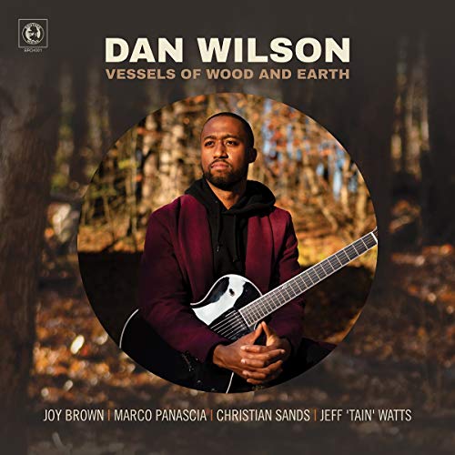 Album cover featuring a man holding a guitar in a wooded area.
