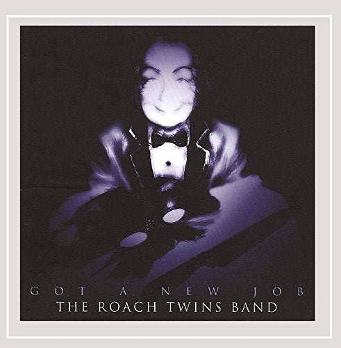 A man in a tuxedo holds a vinyl record on a dark album cover.