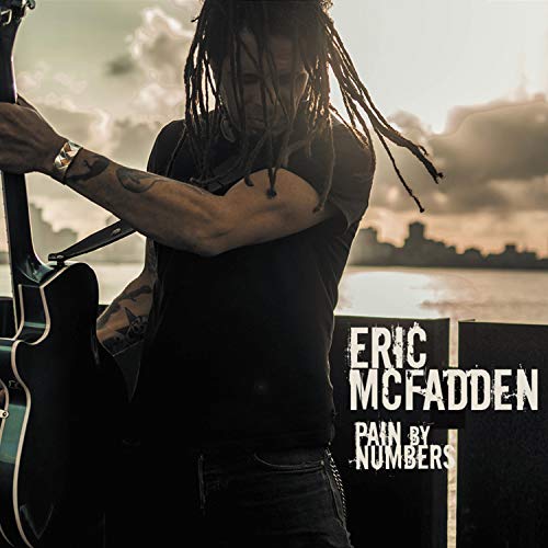 Album cover of "Pain By Numbers" by Eric McFadden, featuring a man with a guitar.