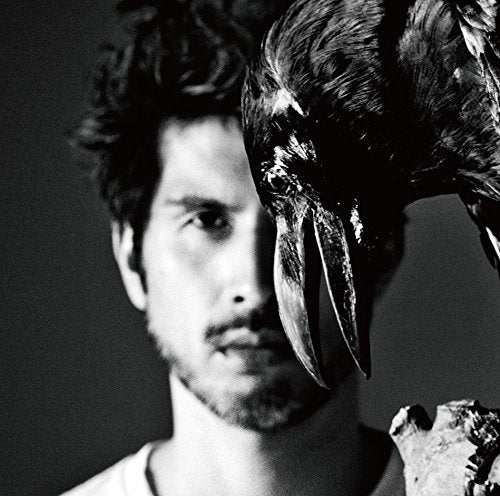 Black and white portrait of a man with a raven on his shoulder.