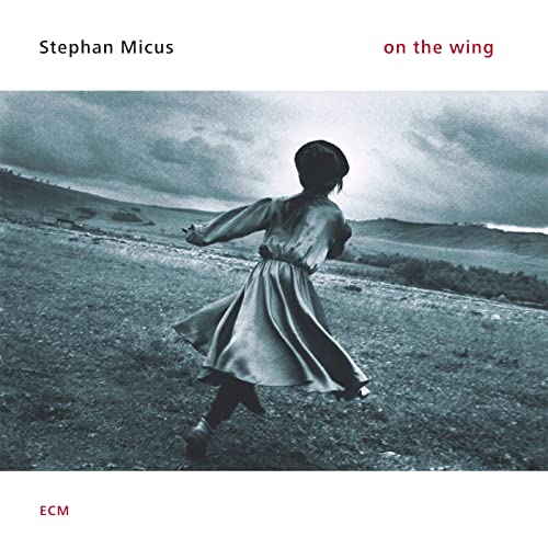 CD cover: child in dress running on a hillside, grey tones.