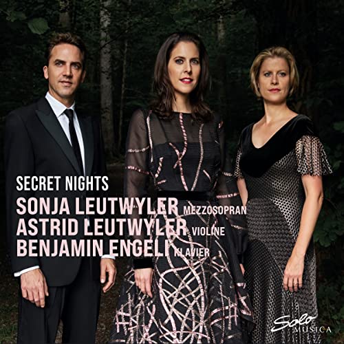 CD cover featuring three formally dressed musicians in a forest setting.
