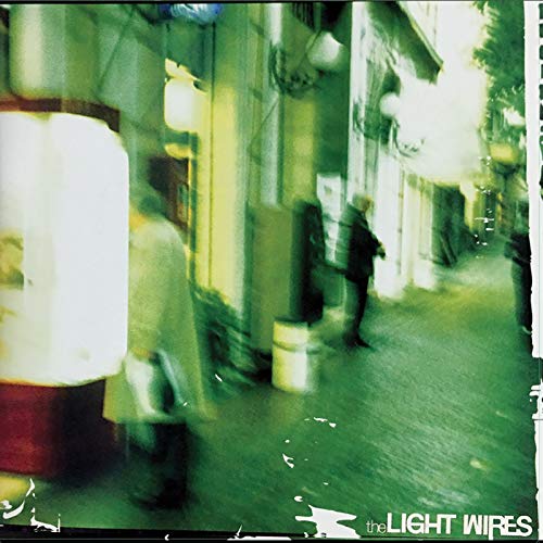 Blurred street scene with figures, album cover for The Light Wires.