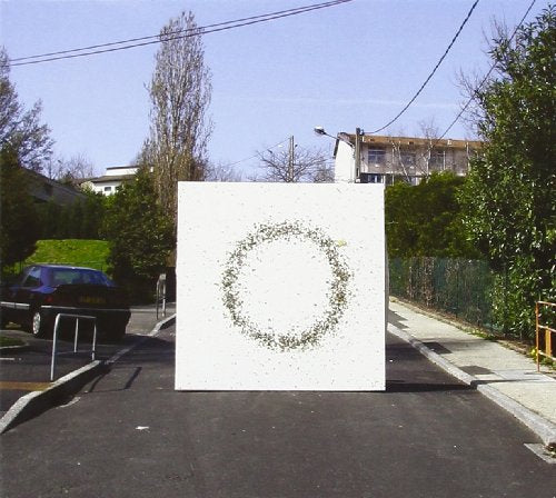 A white square with a green circular design is centered on a street.