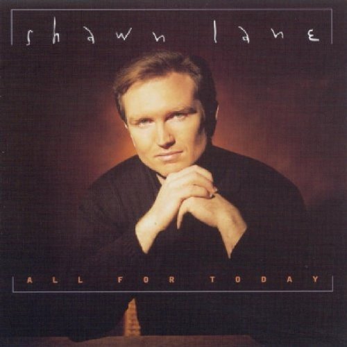"Album cover with a man in black, hands clasped, against a dark background."