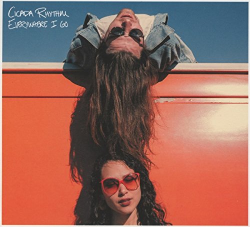 Album cover with a man and woman in sunglasses against an orange wall and blue sky.