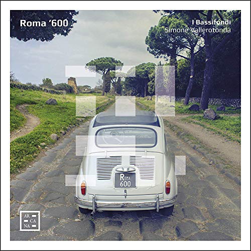 A white vintage car on a cobblestone road, surrounded by trees and grass.