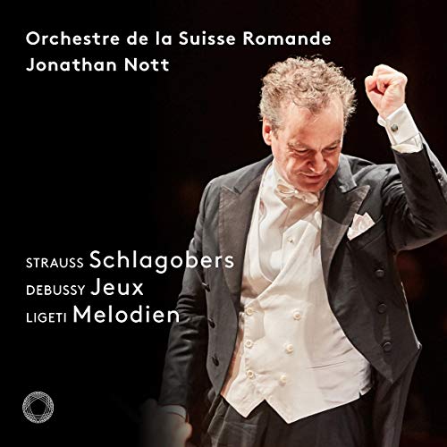 Conductor in a tuxedo with raised fist, against a black background with white text overlay.