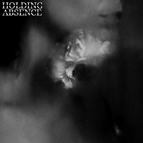 The image is a black-and-white album cover for the band "Holding Absence." The cover features a close-up, blurry photograph of a white flower or plant with delicate petals, positioned centrally and slightly to the right. The background is dark and out of focus, with shades of black and gray. In the top-left corner, the band's name "HOLDING ABSENCE" is displayed in white text. Alt text: Black-and-white album cover with a blurry white flower and band
