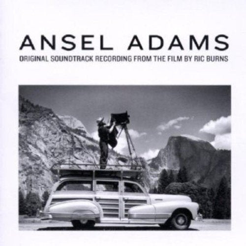 "CD cover with black and white photo of man photographing mountains from a vintage car."