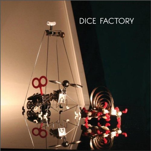 A geometric mobile sculpture with dice and scissors, reflected on a dark surface.