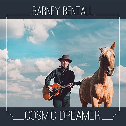 Barney Bentall with a horse, holding a guitar, under a cloudy sky.