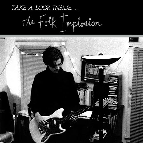 Black and white album cover featuring a man playing a guitar indoors.