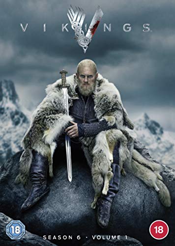 "Man in fur cloak holding sword sits on a rock, snowy mountains behind."