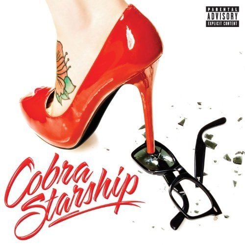 A woman's foot in a red high heel steps on shattered sunglasses on a white background.