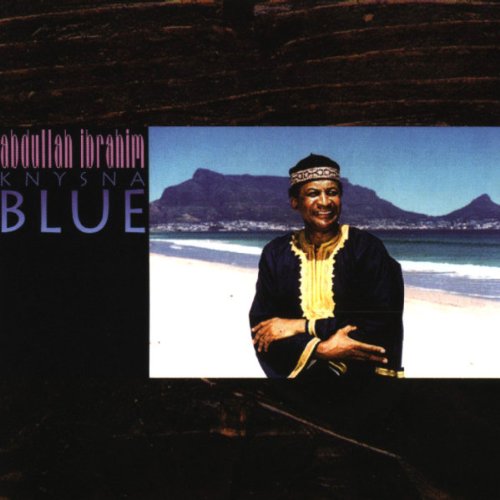 "CD cover with man on beach, mountains in background, and 'BLUE' text."
