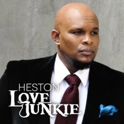 Man in a suit with text overlay "Heston Love Junkie" on a grey background.