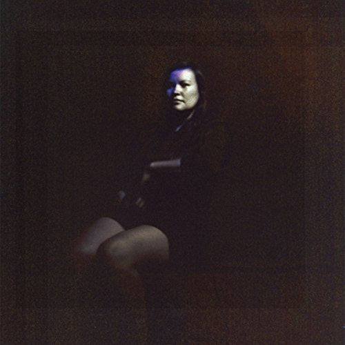 Dark portrait of a person seated, with blue and brown tones.