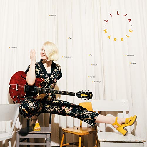 Album cover featuring a woman with a guitar, sitting on chairs.