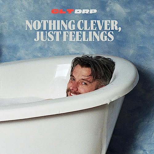 Man’s head emerging from a white bathtub against a blue backdrop.