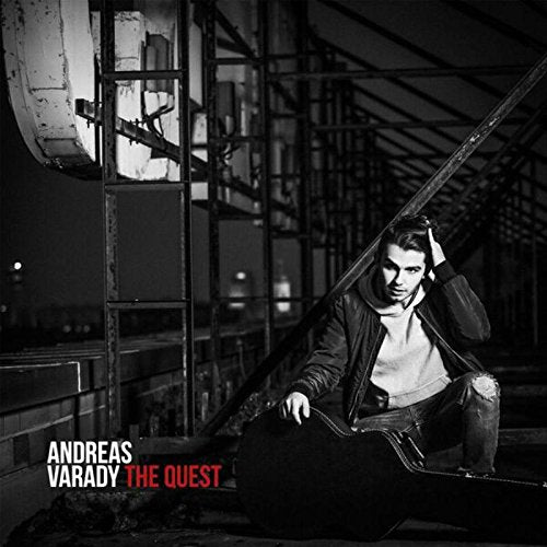 Andreas Varady sits with a cello on a dark, industrial rooftop.