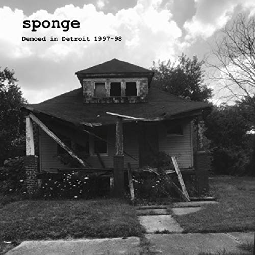 Black-and-white image of a dilapidated house with damaged roof and porch.