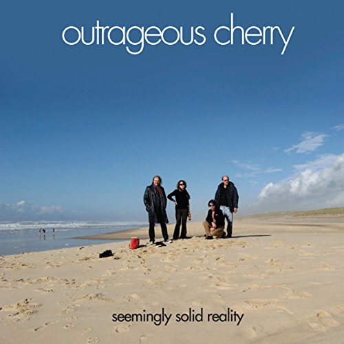 "Album cover featuring four men standing on a sandy beach with blue sky."