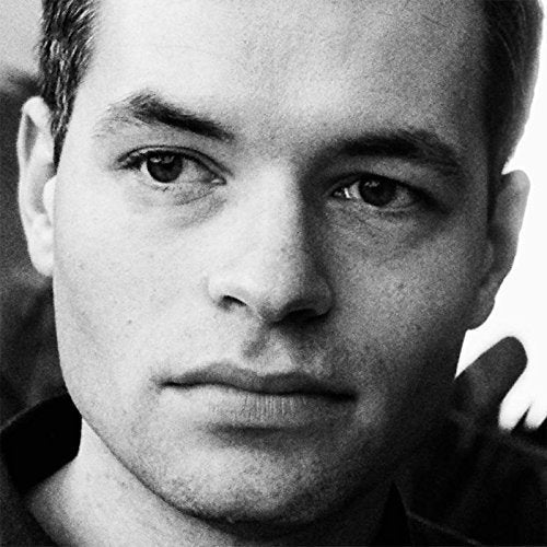 "Black and white close-up portrait of a man with a neutral expression."