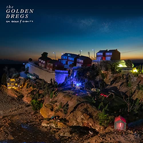 Album cover: a miniature townscape at dusk with glowing lights.