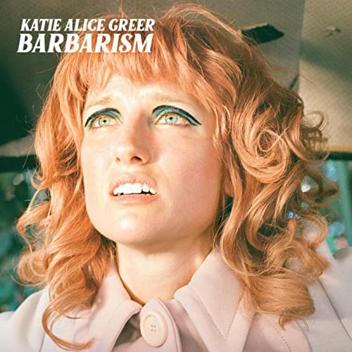 Close-up portrait of Katie Alice Greer with red curly hair and green eyeshadow.