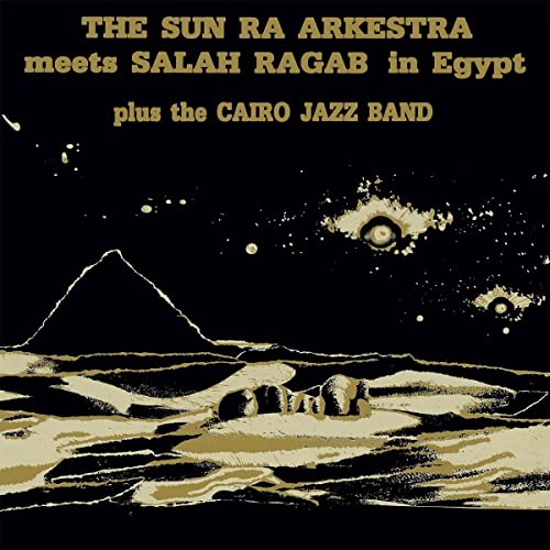 Album cover with pyramids, desert landscape, and celestial imagery in gold and black.