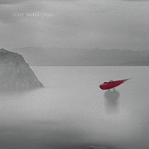 A person stands in foggy water, holding a red umbrella, with a rocky outcrop on the left.