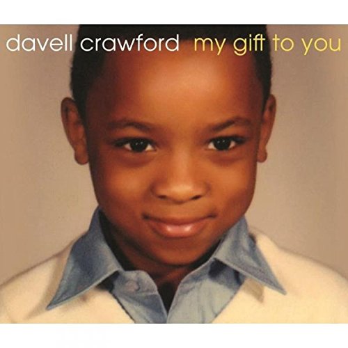 "CD cover featuring a young boy with a warm smile, wearing a white sweater."