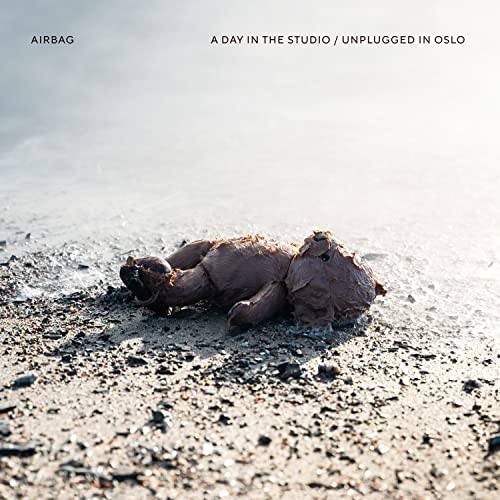 Airbag album cover featuring a worn, stuffed bear on sand.
