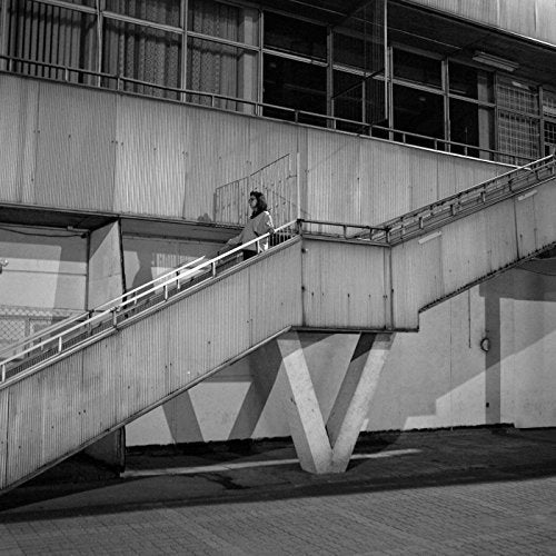 Black and white photo of a person on outdoor concrete stairs.