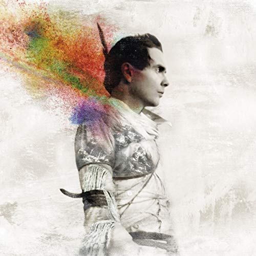The alt text for the image is: "Man in white shirt with colorful splatter behind him."