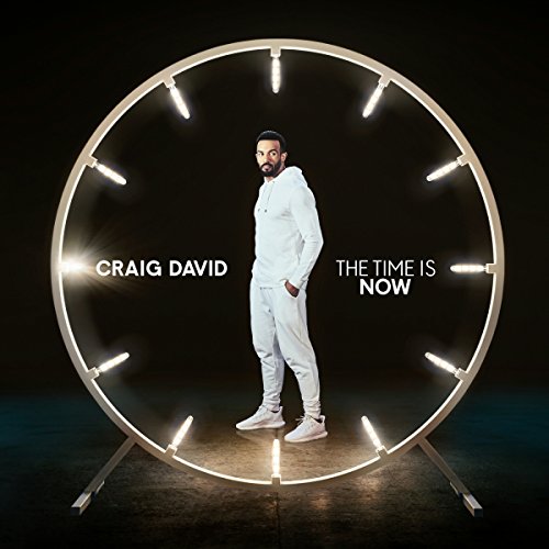 "Man in white outfit stands inside a lit-up circular frame on a dark background."