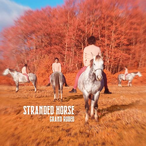 People on horseback in a field with orange-red trees, album cover.
