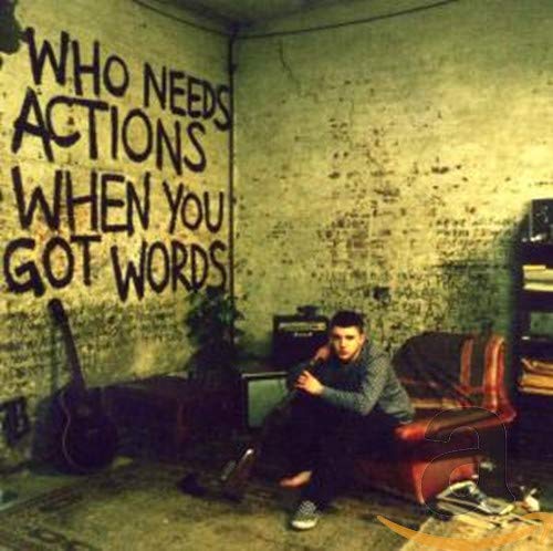 Album cover: man seated before graffiti-covered wall with guitar.