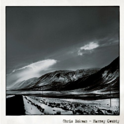 Black and white photograph of snow-covered mountains and a valley with the artist's name.