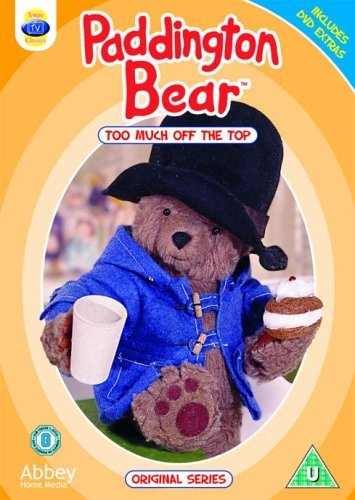 Paddington Bear in a blue coat, holding a mug and sandwich.