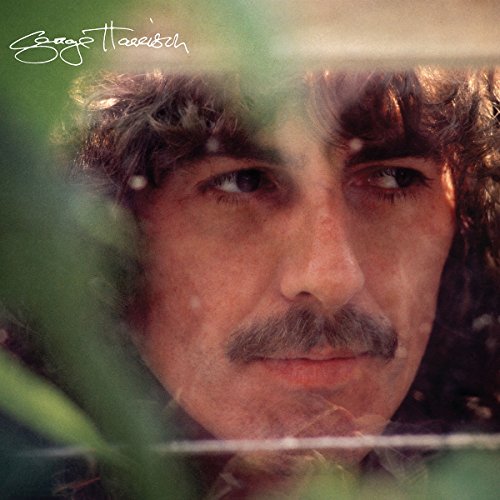 Close-up portrait of George Harrison with foliage framing his face.