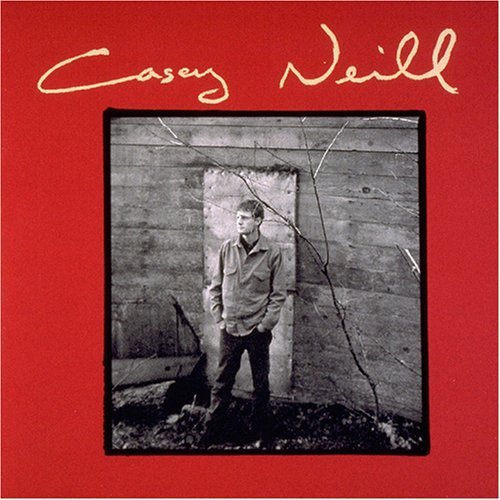 "Album cover with red background, black and white photo of man standing by a wall."