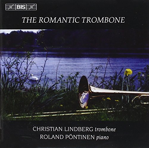 Trombone lies on a wooden fence by a serene lake with flowers and grasses.