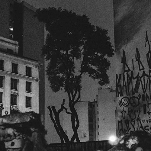 Black and white photo of a tree in an urban setting with graffiti.