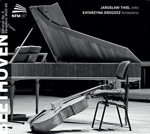 Black and white image of a cello and grand piano on a stage.