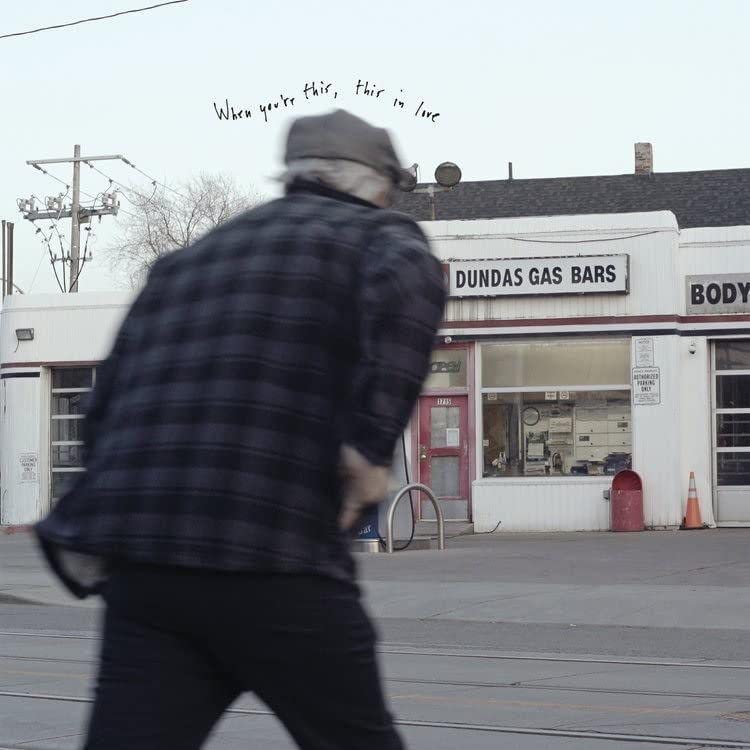 Blurred figure walking past a gas station with text overlay.