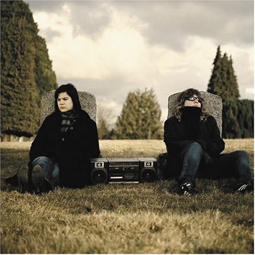 "CD album cover with two people sitting by a boombox in a cemetery."