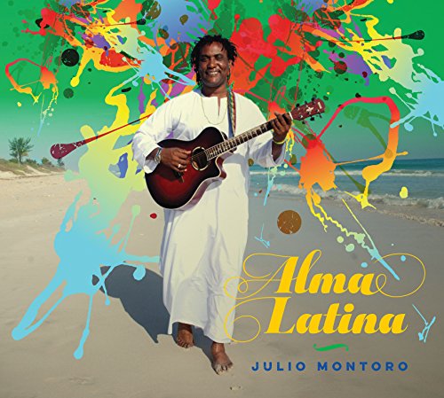 Julio Montoro holds a guitar on a beach with colorful paint splatters.