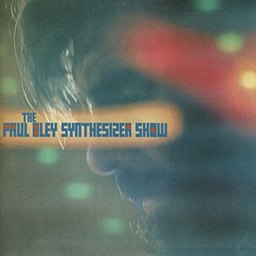 "Album cover with a close-up of a man's face and blue text."